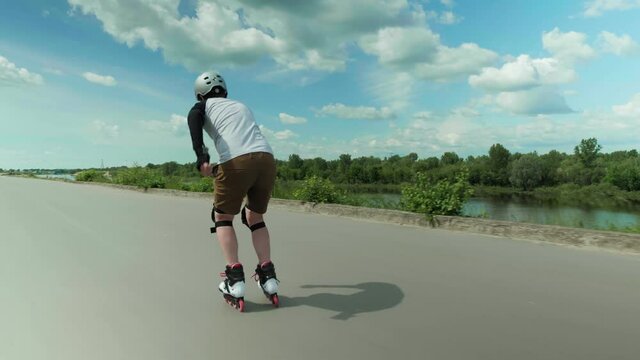 Sportsman in helmet and inline skates accelerating and rolling forward outdoors