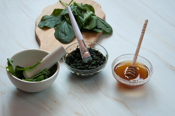 Natural home skin care. Ingredients of a face mask. Plantain puree (Plantago major), honey and finished composition in close-up on a marble background. Selective focus.