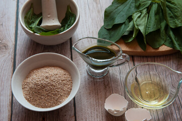 Natural home skin care. Ingredients of a face mask. Plantain leaf juice (Plantago major), oat bran and egg white close-up on a wooden background. Selective focus.
