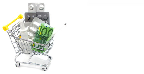 A variety of pills in blister packs in a mini shopping trolley cart with money on white background.Health and expensive medicine. Online shopping concept in pharmacy. Space for text. Internet commerce