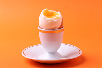 soft-boiled sunny side up halves of chicken eggs on the white plate bright orange background. close up shot. minimalism concept