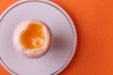 soft-boiled sunny side up halves of chicken eggs on the white plate bright orange background. close up shot. minimalism concept