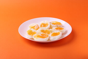 soft-boiled sunny side up halves of chicken eggs on the white plate bright orange background. close up shot. minimalism concept
