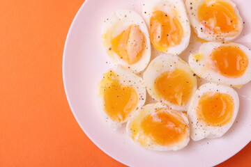 soft-boiled sunny side up halves of chicken eggs on the white plate bright orange background. close up shot. minimalism concept