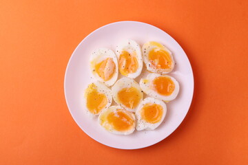 soft-boiled sunny side up halves of chicken eggs on the white plate bright orange background. close up shot. minimalism concept