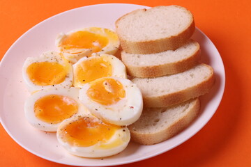 soft-boiled sunny side up halves of chicken eggs on the white plate bright orange background. close up shot. minimalism concept