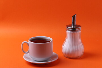 tea cup and a sugar pot bottle on orange