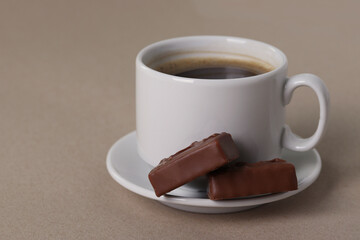black espresso in a white ceramic cup and a saucer  on the light beige background. close up shot, minimalism style