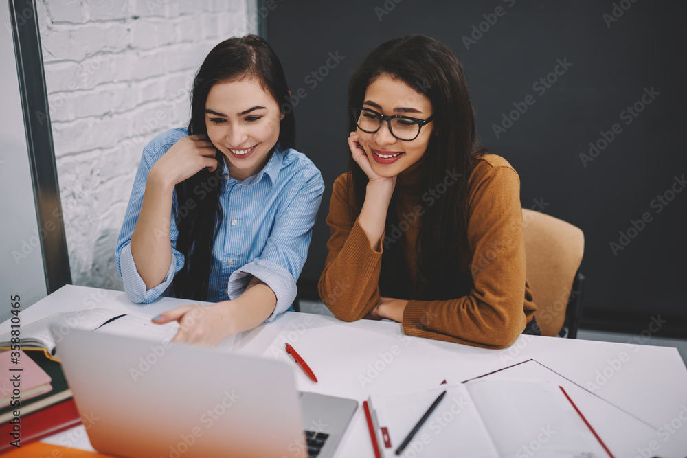Poster smiling girls watching movie on laptop computer making break during learning process in college camp
