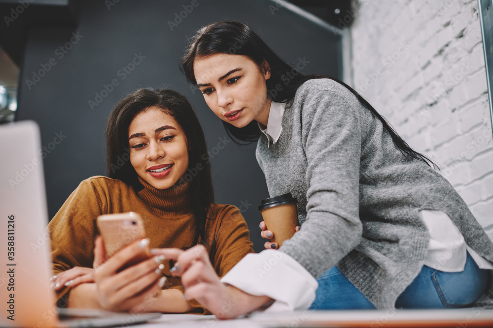 Poster hipster girl helping her friend installing useful app for learning languages during studying in coll