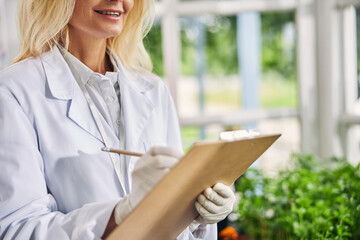 Contented Caucasian female biological scientist examining seedlings