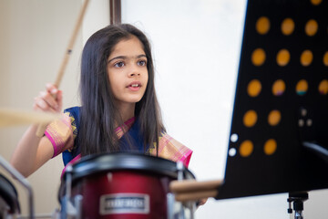 British Indian girl practices the drums wearing a traditional saree or sari. 