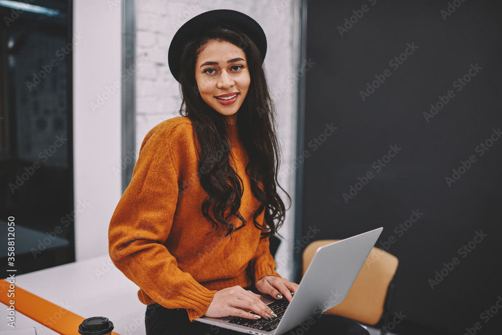 Poster half length portrait of attractive smiling woman making researches in network during working on lapt