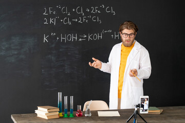 Teacher in whitecoat doing record of chemistry lesson for his online audience