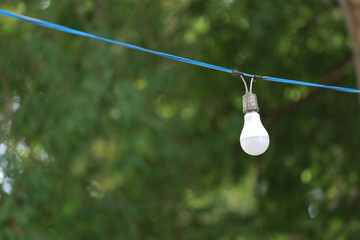 Obraz premium One white light bulb connected to an old blue electric wire