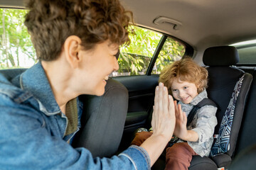 Cheerful female and her little son in casualwear giving each other high five