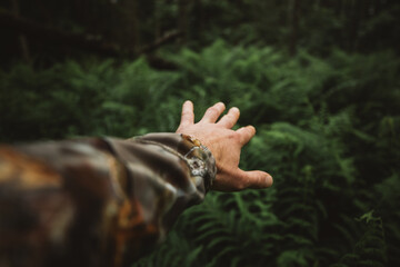 Close up of male hands in the green rainy wilderness forest. Survival travel,lifestyle concept.	