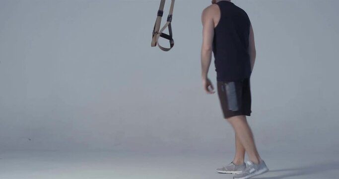 Fitness training TRX exercises and leave after done. Video tutorial in studio isolated on light background, man doing push-ups with one leg up. Fitness concept. Prores 422.
