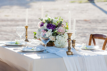 Table setting served and decorated for party event with plates, glasses, candles, napkins, lamps, flowers and invitations. Guests table, Wedding reception, Birthday, anniversary. Holiday evening