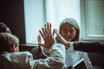 High five gesture of office staff after successful brainstorming. Team building concept. Selective focus on human hands. Close up. Tinted image.