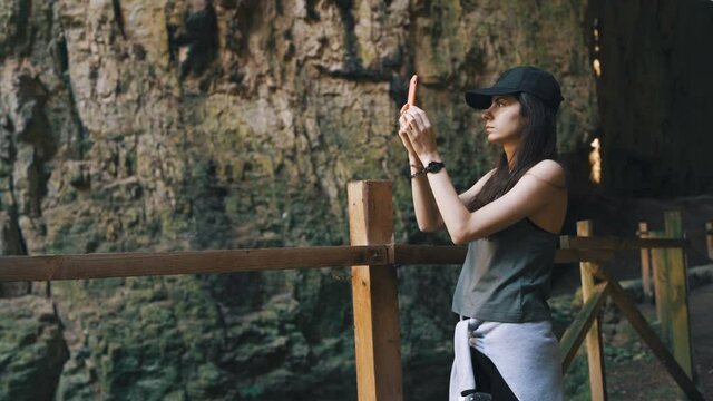 Tourist girl taking photos of Devetashka cave in Bulgaria while in holiday trip