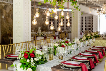 Table setting served and decorated for party event with plates, glasses, candles, napkins, lamps, flowers and invitations. Guests table, Wedding reception, Birthday, anniversary. Holiday evening