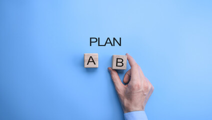 Businessman hand choosing plan B option. top view on blue backgrounnd