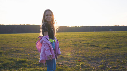 Girl 12 years old posing in a field at sunset.