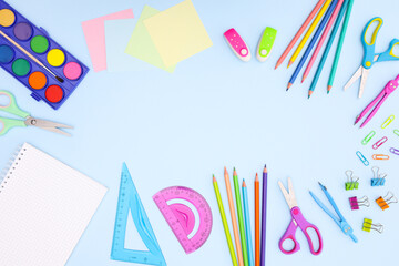 Back to school concept on blue background. School supplies and open notebook on pastel blue background 