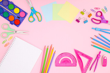Back to school concept on pink background. School supplies and open notebook on pastel pink background 