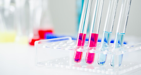 Clear glass test tube There are chemicals, red and blue inside. There is a lot of testing equipment on the white table in the laboratory. There is a copy space concept. Research, weaving