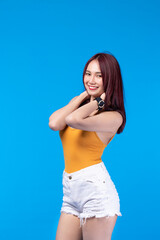 Obraz premium Fashion of a beautiful young asian woman in a pretty yellow vest White shorts. Girl posing smiling on blue background. fashion beauty and style.