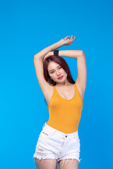 Fototapeta na wymiar Fashion of a beautiful young asian woman in a pretty yellow vest White shorts. Girl posing smiling on blue background. fashion beauty and style.
