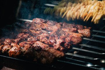 Meat and potatoes on skewers are cooked on a grill 