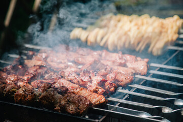 Meat and potatoes on skewers are cooked on a grill 