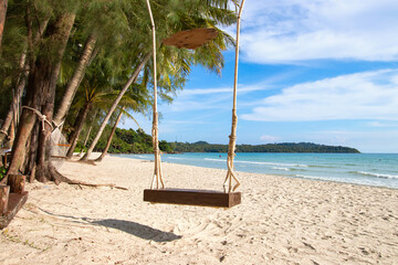Swing hanging on coconut palm trees on tropical paradise beach with coconut palm trees on island. Relaxation time beautiful beach travel summer holiday concept.