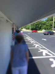 Social Distancing Standing in Line during  COVID-19 Coronavirus quarantine lock down because of customer limit in store in Rhode Island RI USA Front of Food Store Painted lines with pedestrian logos.