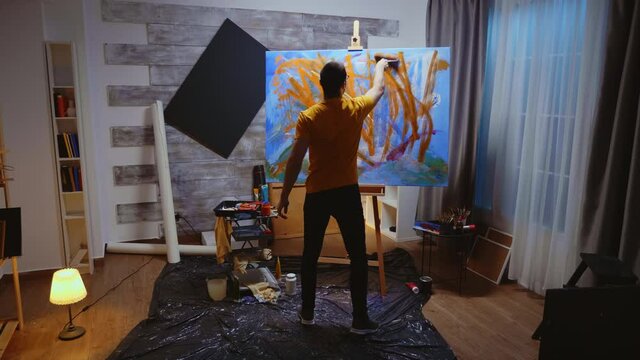 Contemporary artist in studio painting a masterpiece on large canvas. Modern artwork paint on canvas, creative, contemporary and successful fine art artist drawing masterpiece