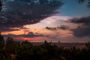 dramatic sunrise view of barcelona at dusk from guinardo park, with sun rising through clouds and cityscape with tres xemeneies