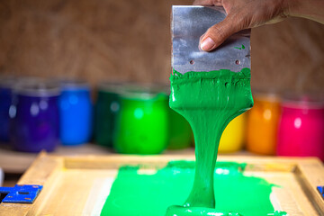 green color dripping from hand screen printing during printing tee shirt in tee shirt factory.