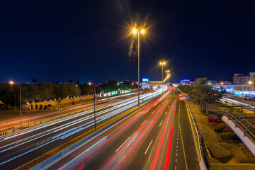 An evening time busy street view of Muscat road with vehicle light trails and street lights.