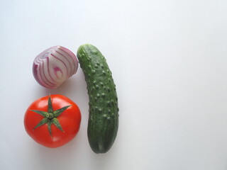 Tomato cucumber and red onion on a white background close-up in the lower corner.