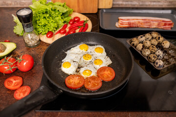 Several fried quail eggs and tomato slices sprinkled with ground black pepper