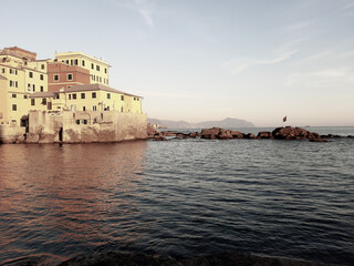 Obraz premium Genova, Italy - 06/18/2020: Beautiful photography of the sunset over the sea and clouds reflection on the water. Panoramic view to the ligurian coast in spring days.