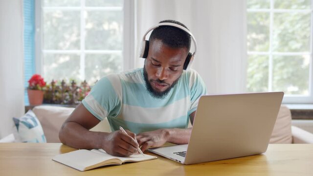 Focused african businessman wear headphones study online watching webinar