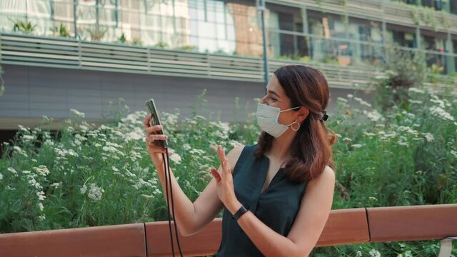 Lifestyle during covid-19, quarantine. Young woman in medical protective mask making selfie during walking in summer park, video chat conference with friends, tourist after covid