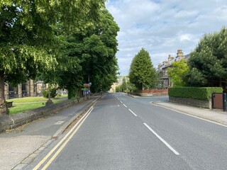 Fototapeta na wymiar Main road, with old trees and houses, leading into the centre of, Shipley, Bradford, UK