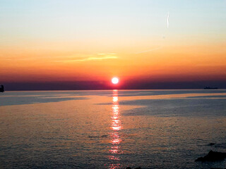 Genova, Italy - 06/18/2020: Beautiful photography of the sunset over the sea and clouds reflection on the water. Panoramic view to the ligurian coast in spring days.