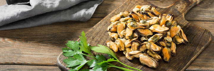 Mussel meat on a wooden Board on a brown wooden table. Clams on the serving Board. Rustic style. Banner with space for text