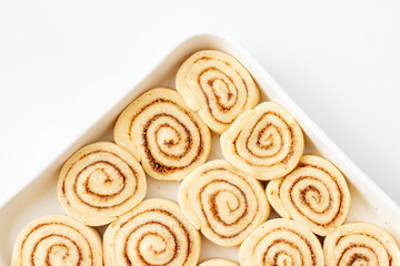 Obraz na płótnie Canvas Close-up of Tasty raw cinnamon rolls in baking dish on white table